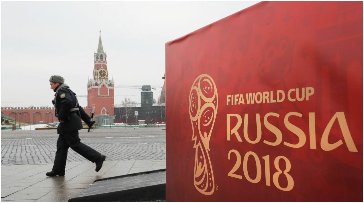 Un oficial del Ministerio de Interior ruso pasa junto a un cartel de la Copa del Mundo frente al palacio del Kremlin, donde este viernes tendrá lugar el sorteo de la primera fase del torneo que distribuirá a los 32 equipos en ocho grupos, en Moscú.