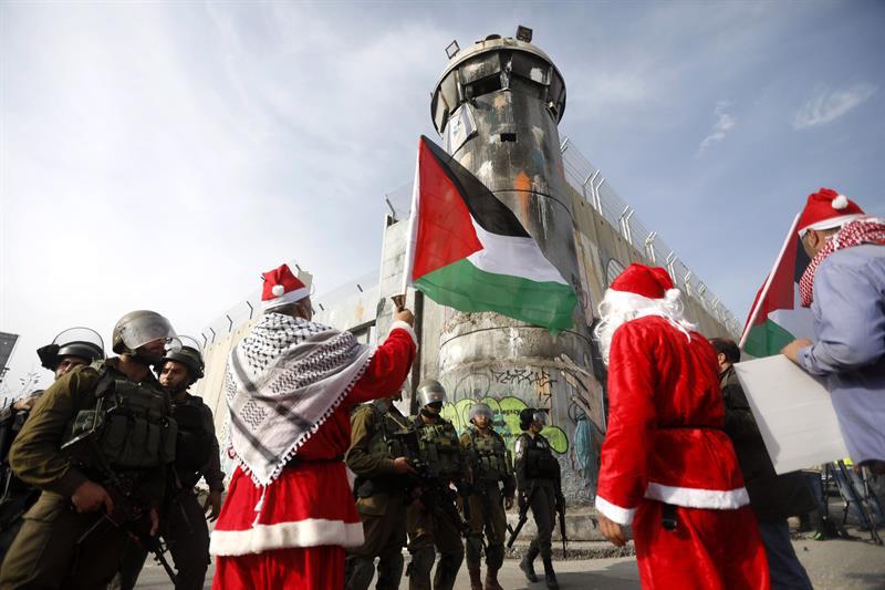 Un palestino vestido como Santa Claus frente a soldados israelíes durante una protesta en la ciudad cisjordana de Belén.