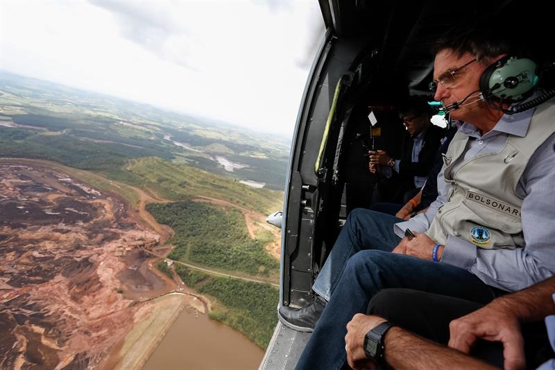 Fotografía cedida por la Presidencia de Brasil que muestra al presidente Jair Bolsonaro mientras sobrevuela la zona afectada por una avalancha tras la rotura de una represa minera, este sábado, en Brumadinho (Brasil). 
