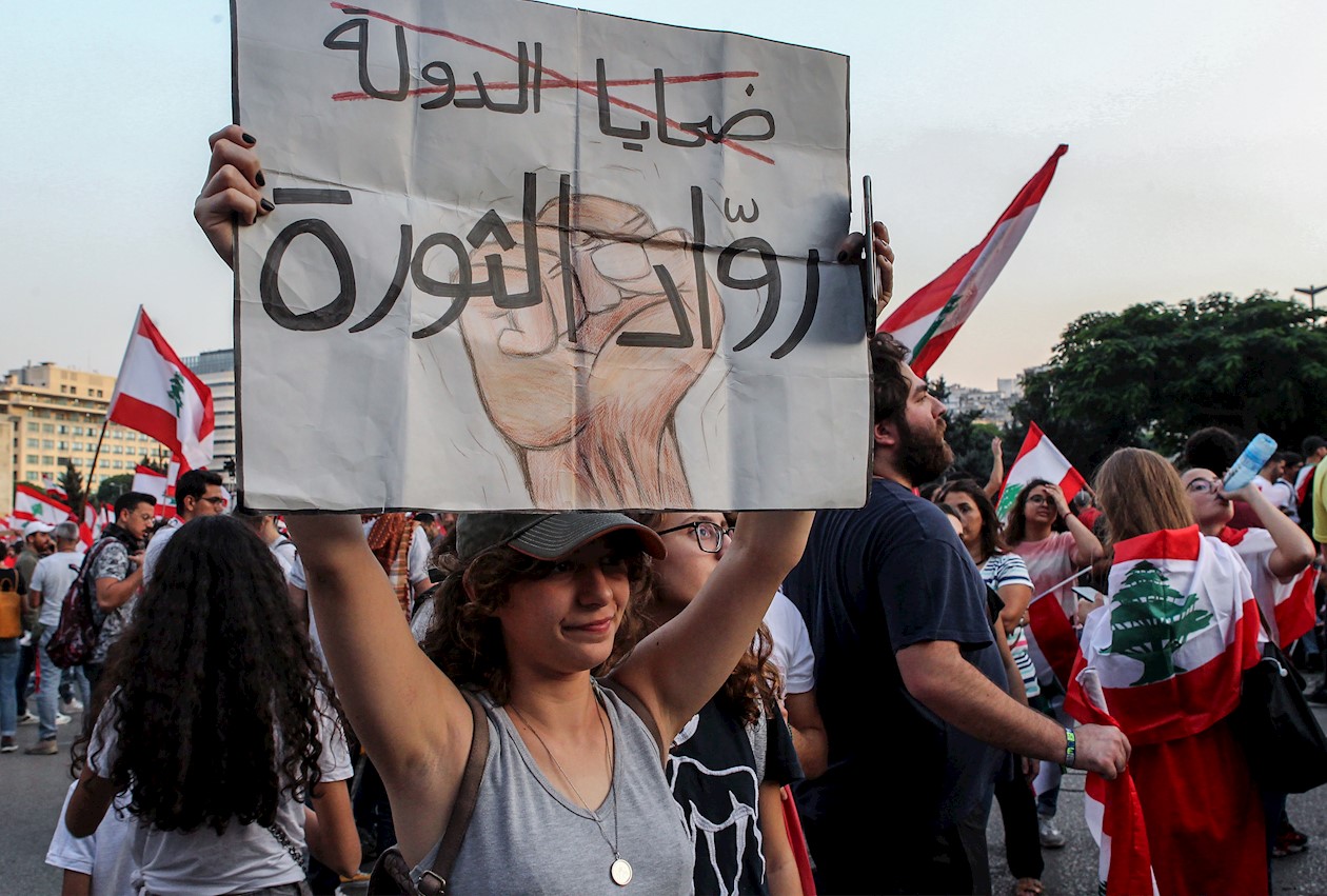 Los manifestantes llevan pancartas, ondean banderas libanesas y gritan consignas antigubernamentales durante una protesta frente al palacio de gobierno en el centro de Beirut, Líbano.