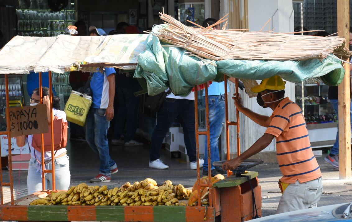 Un vendedor ambulante transporta sus frutas pero se protege.