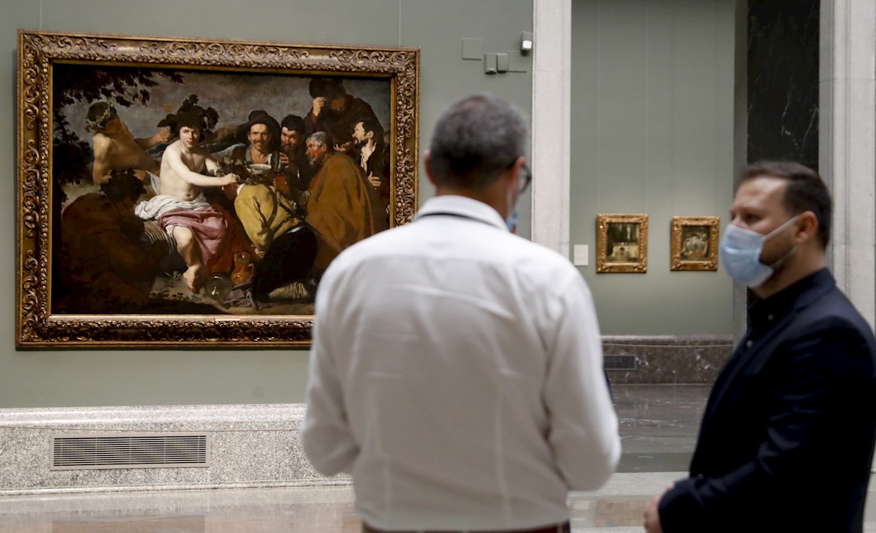 Dos periodistas conversan frente a la obra 'El Triunfo de Baco' de Diego Velázquez durante la presentación a medios de "Reencuentro".