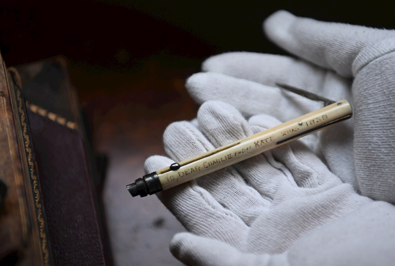 Un empleado del museo posa con un bolígrafo, un lápiz y un sacapuntas multiusos que su esposa Catherine le dio al escritor británico Charles Dickens para la Navidad de 1838 en la casa en la que compartieron esa Navidad.