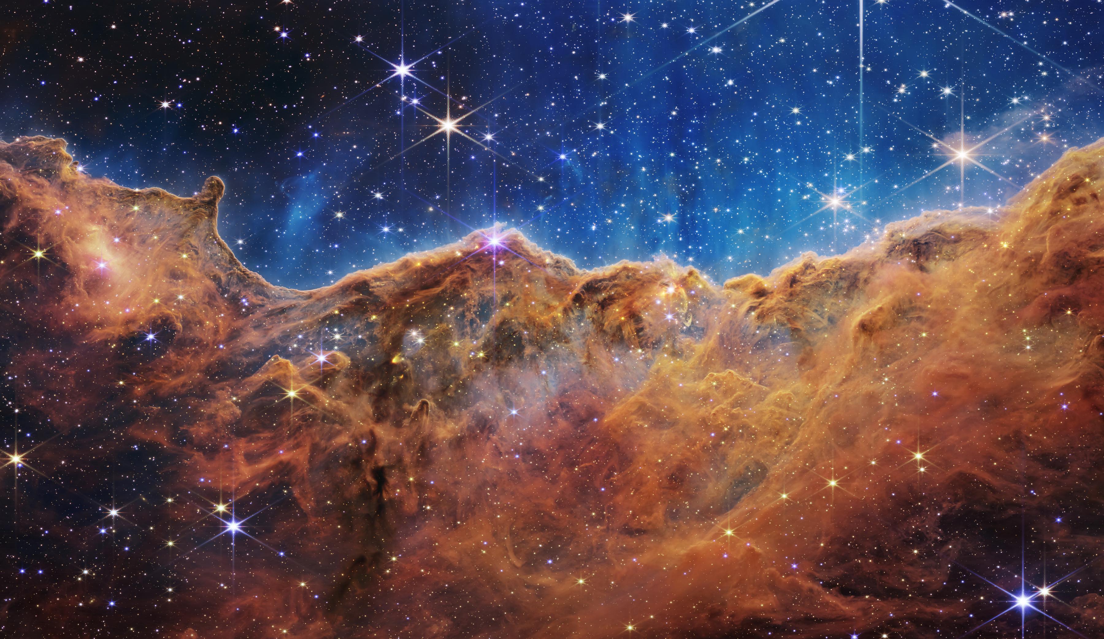 Imagen del borde de una región cercana y joven donde se forman estrellas, llamada NGC 3324, en la Nebulosa de Carina, que se asemeja a un paisaje de "montañas" y "valles" salpicados de estrellas brillantes.