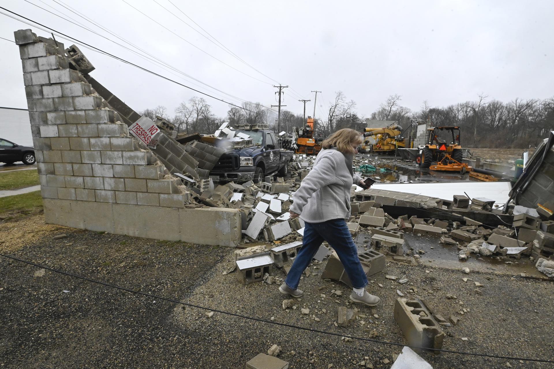 Una mujer pasa frente a un negocio destruido tras un tornado en Belvidere, Illinoi