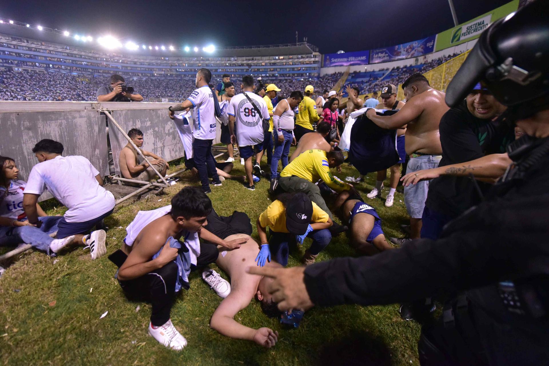  Fanáticos auxilian a personas durante una estampida en el Estadio Cuscatláán