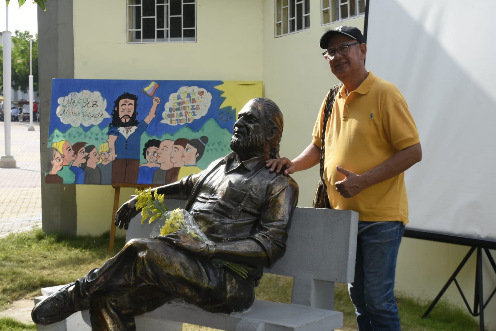 Rafael Rojas tomándose una foto con la estatua de Alfredo Correa.