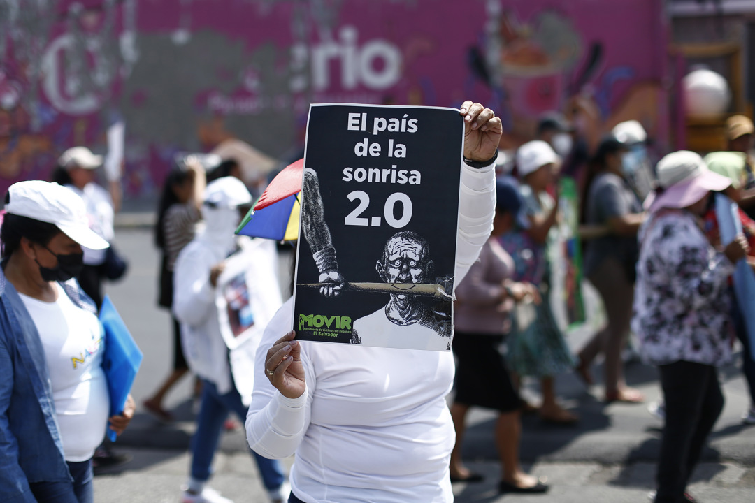Mujer sosteniendo un cartel con la descripción “El país de la sonrisa 2.0”.