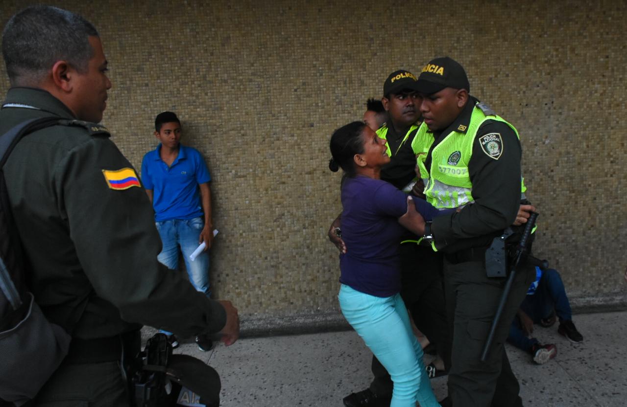 Momento en que la Policía detiene a la mujer para que no siga la agresión al camarógrafo.