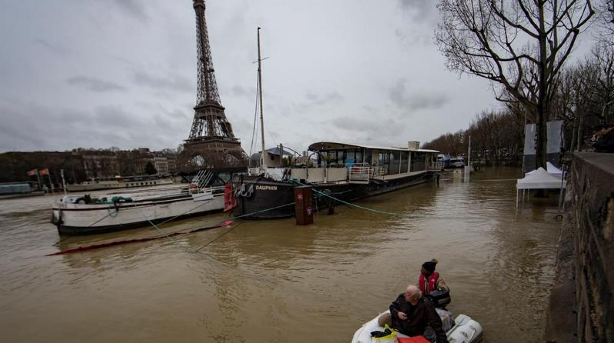 Un hombre transporta a un pasajero en un bote en el desbordado río Sena, París.