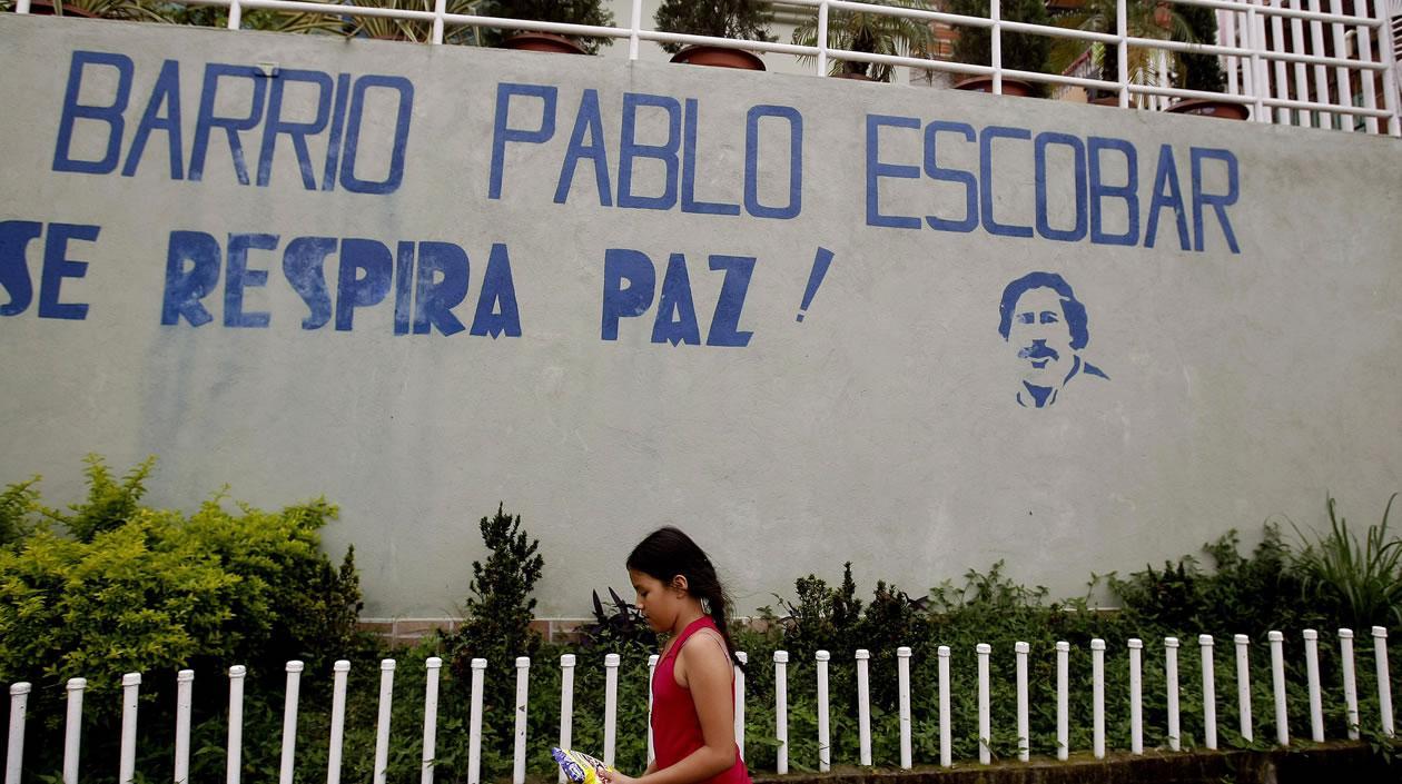 Una niña camina frente al mural que da la bienvenida al barrio Pablo Escobar en Medellín