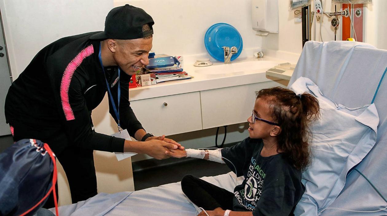 El futbolista francés Mbappé saluda a una niña durante la visita al hospital infantil parisino Necker.