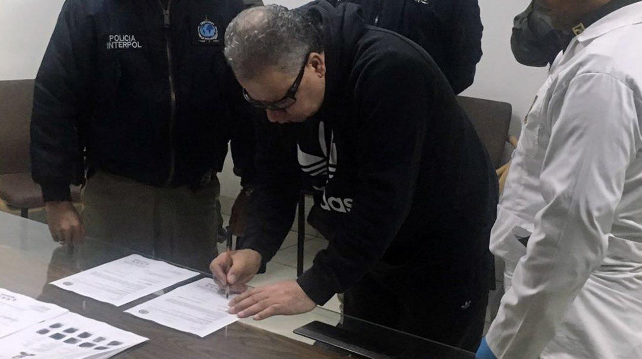 Exjefe paramilitar Daniel Rendón Herrera firmado documentos durante su extradición.