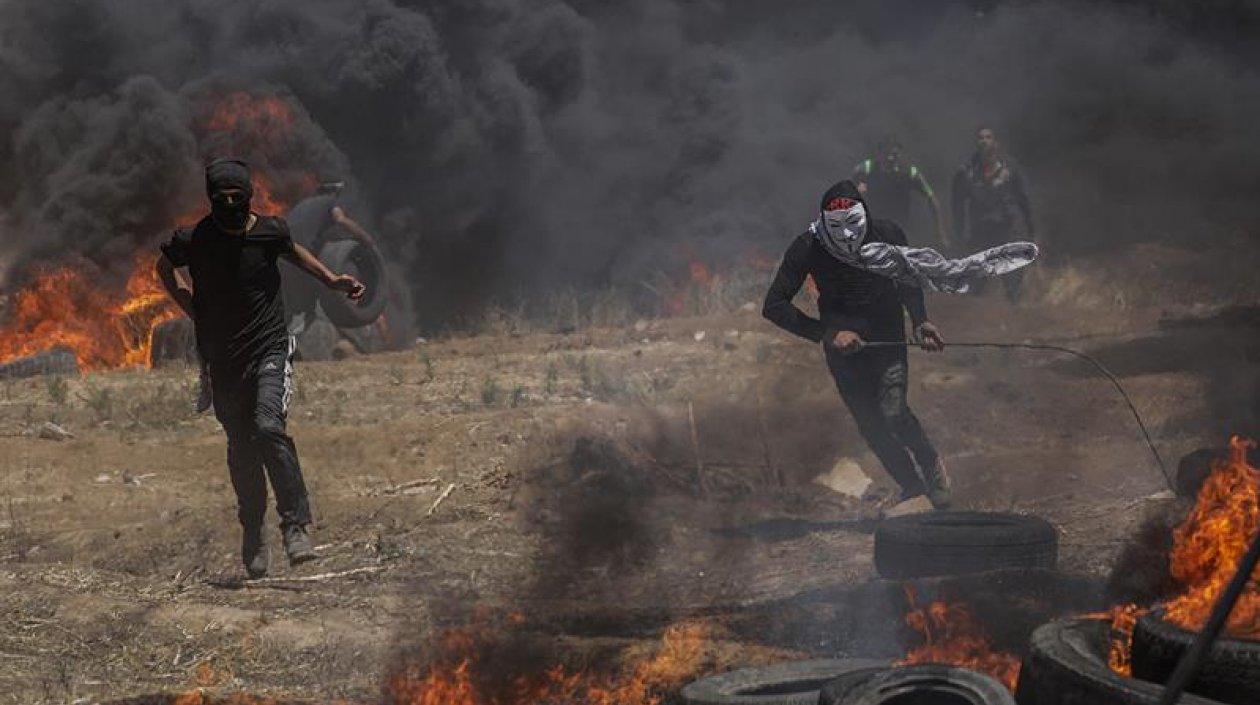 Dos palestinos corren en busca de refugio durante los enfrentamientos surgidos tras las protestas convocadas cerca de la frontera con Israel en el este de la franja de Gaza.