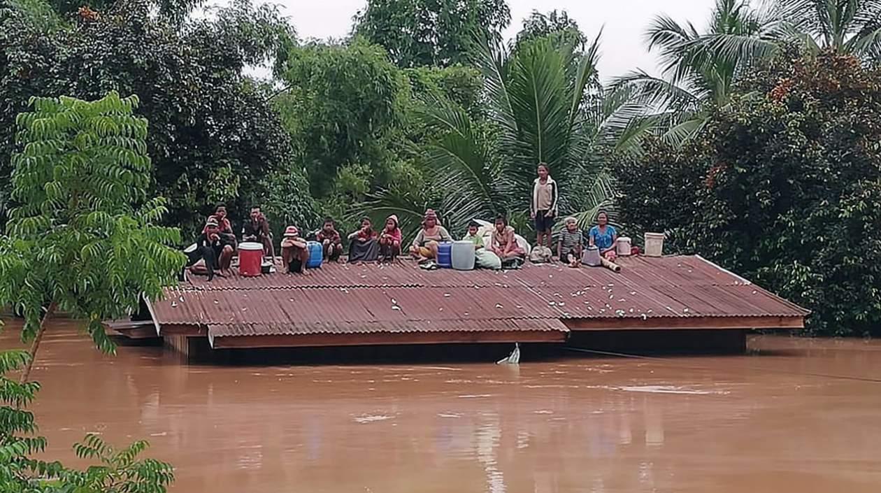 Un grupo de personas aguarda en lo alto de un tejado en una zona inundada tras el derrumbe de una presa hidroeléctrica en un pueblo cercano a la provincia de Attapeu, en Lao