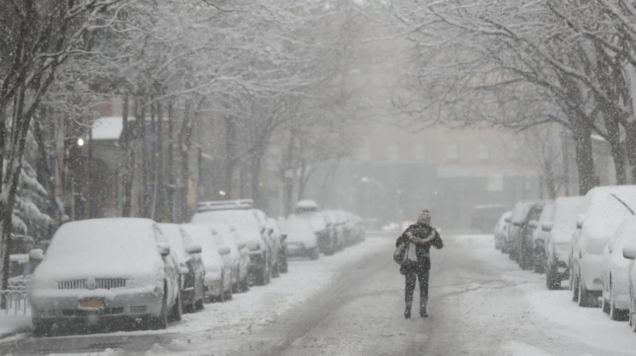 Una mujer camina por la carretera durante la tormenta de nieve en Nueva York