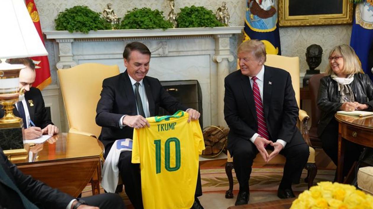 El presidente de Estados Unidos, Donald Trump (2d), recibe una camiseta de la selección brasileña de fútbol durante una reunión mantenida con su homólogo brasileño, Jair Bolsonaro (2i), en la Casa Blanca.