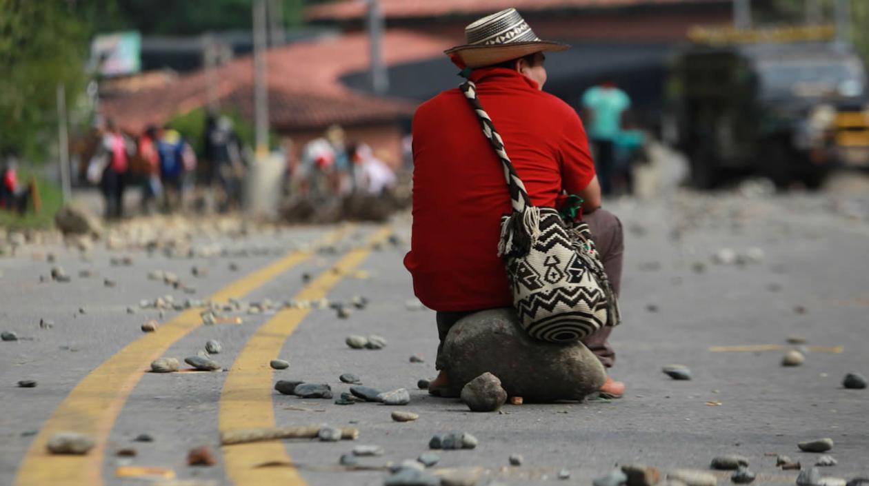 Indígena espera sobre una roca durante el bloqueo de la vía Panamericana en el municipio de Caldono, Cauca
