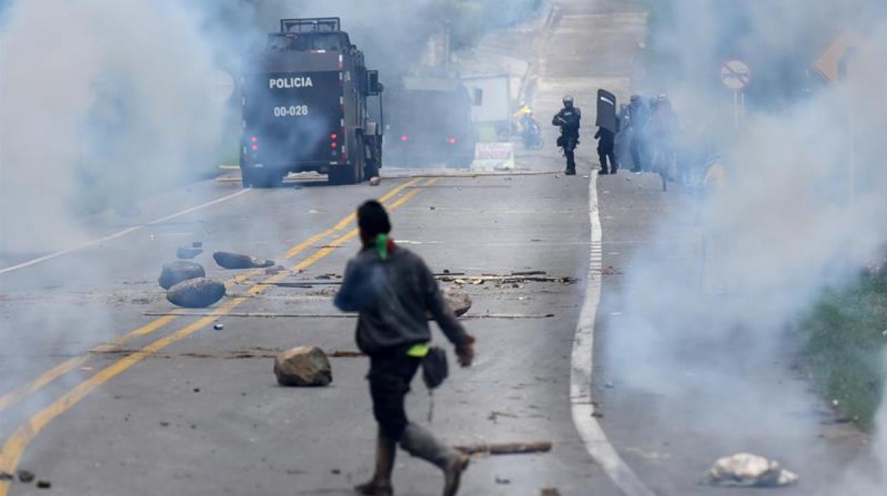 Manifestantes indígenas corren durante un enfrentamiento con el escuadrón antidisturbios de la policía,  en la vía panamericana.