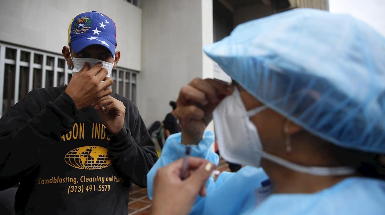 Un hombre venezolano recibe un tapabocas este lunes en la Alcaldía de Cali.