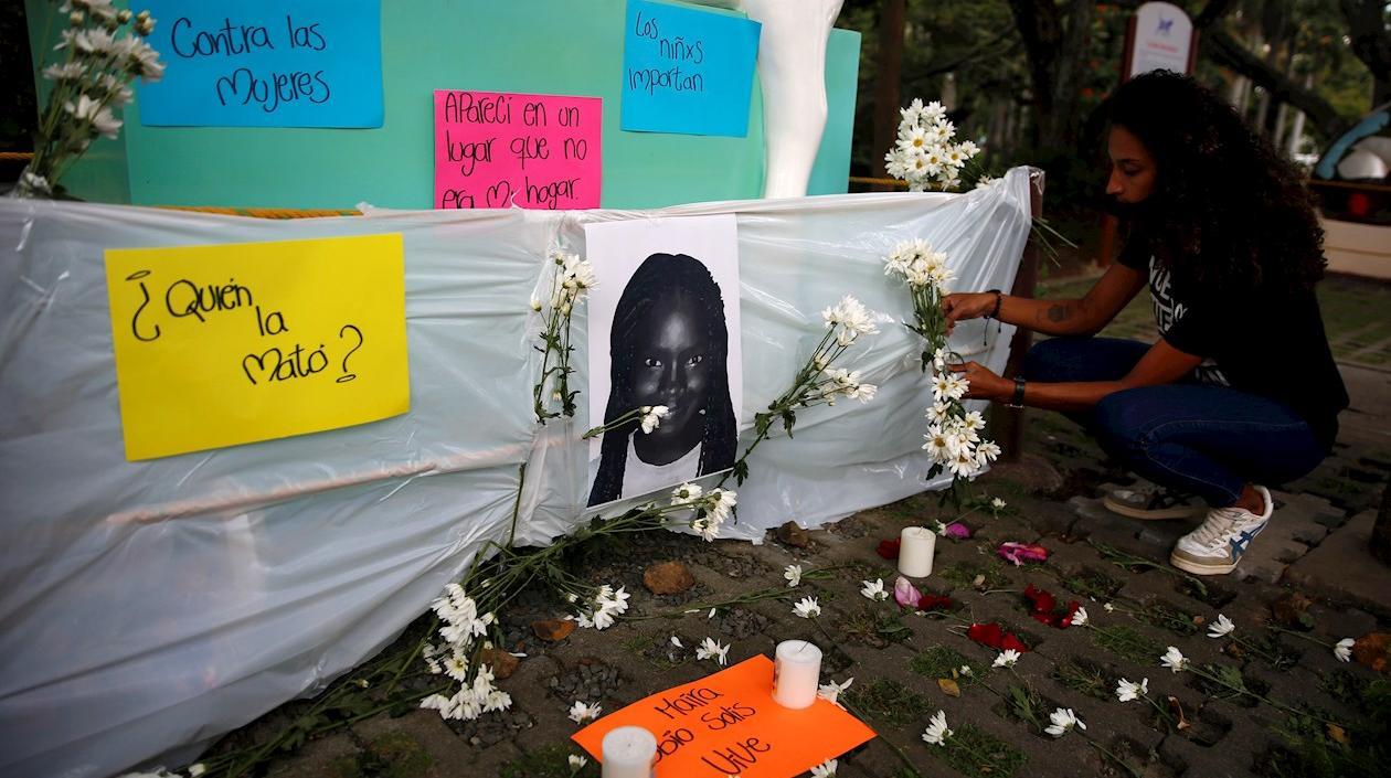 Una mujer deja flores junto a la foto de la niña Maira Alejandra Orobio, asesinada con signos de tortura y abuso sexual en Guapi.