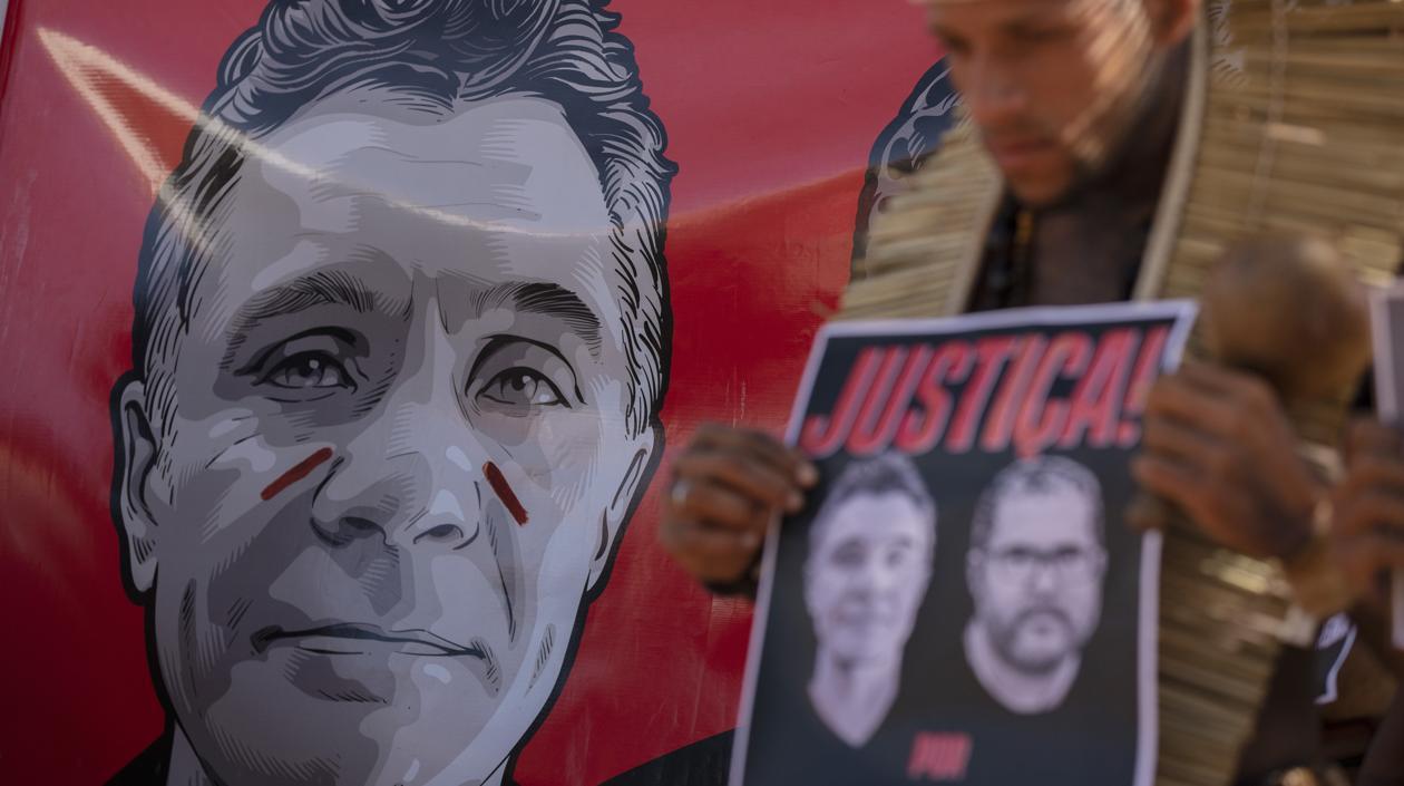 Un hombre sostiene un cartel con retratos del periodista Dom Phillips y el indigenista Bruno Araújo.