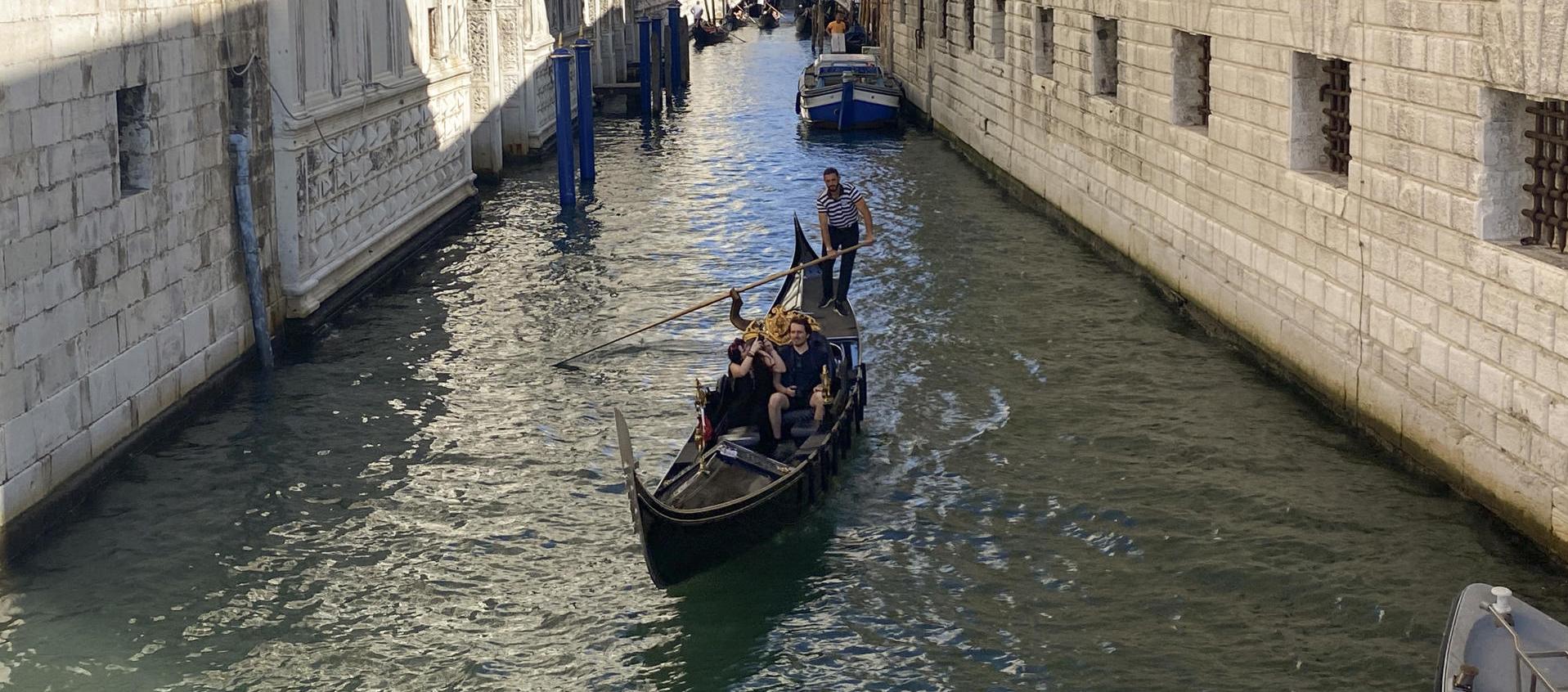 Una pareja disfruta de un viaje en góndola por un canal de Venecia