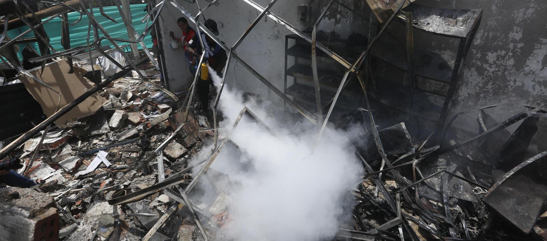 Un hombre usa un extintor en los escombros de una vivienda destruida por un ataque con carro bomba en el Cauca