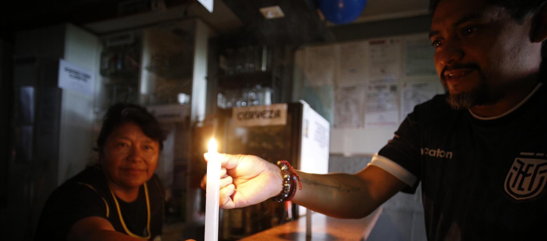 Ciudadanos ecuatorianos encienden una vela ante los apagones de los últimos días. 