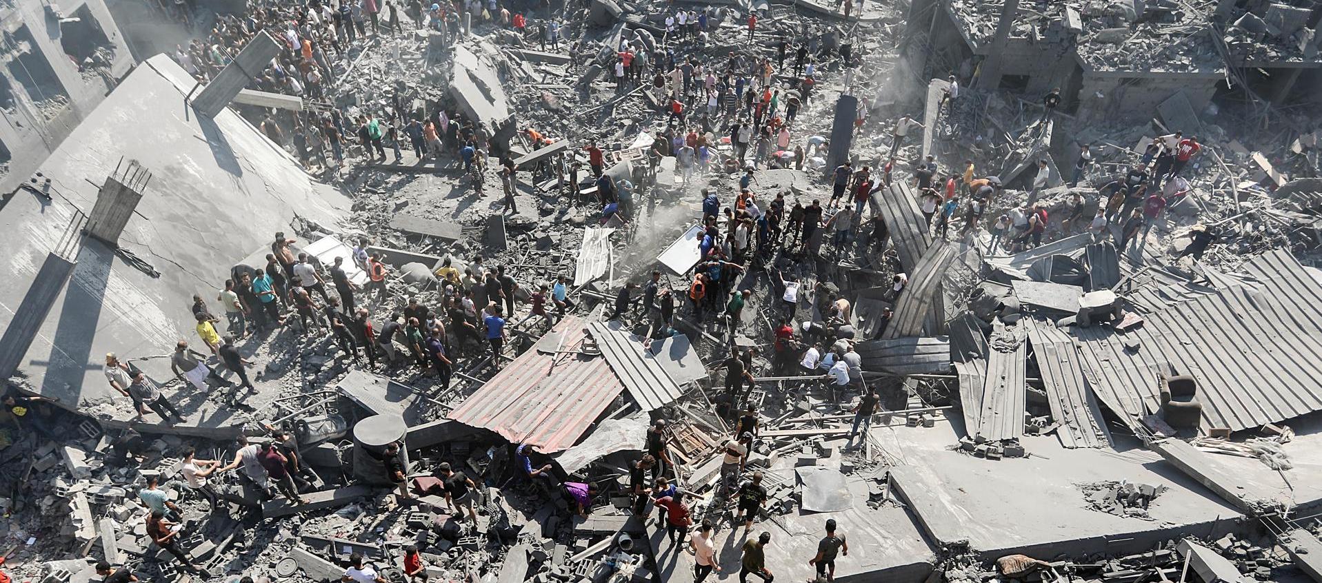 Palestinos buscan víctimas y supervivientes entre los escombros de un edificio residencial derribado.