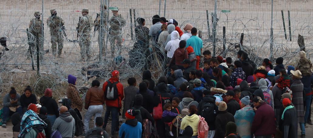Migrantes tratan de cruzar las vallas fronterizas en Ciudad Juárez.