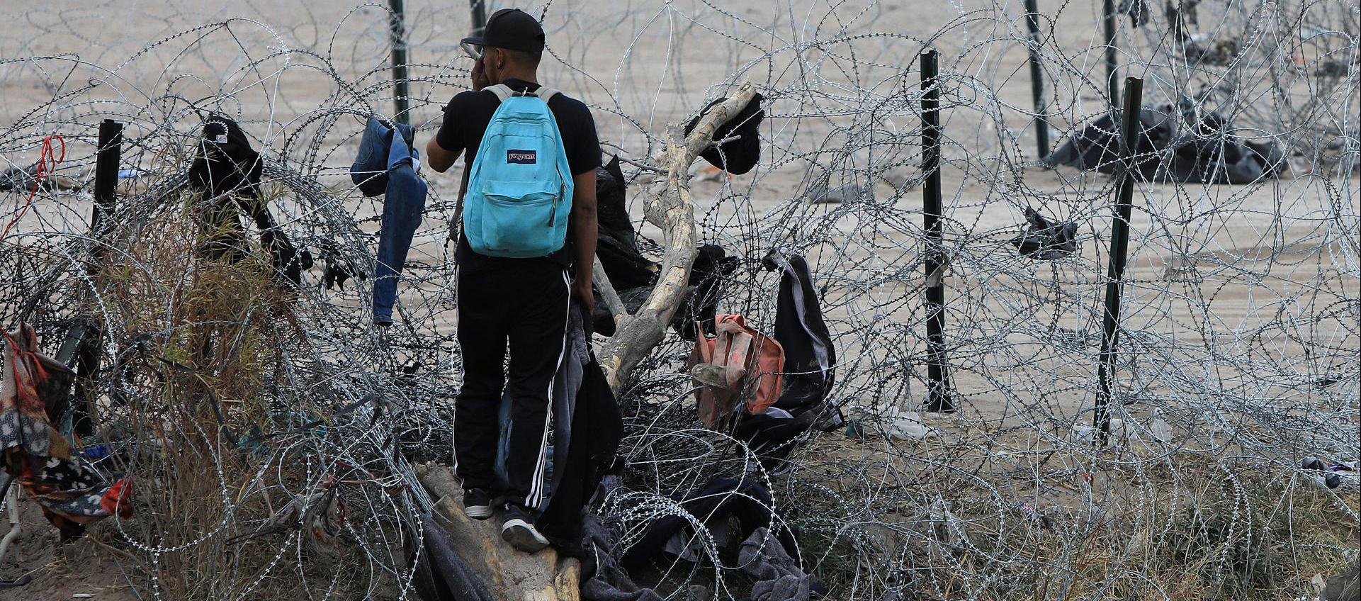 Migrantes buscan cruzar una alambrada en frontera entre México y EE.UU.