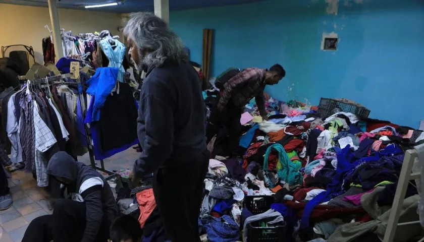 Un grupo de migrantes venezolanos selecciona ropa donada.