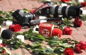 Cámaras y micrófonos de diferentes medios junto a rosas, en señal de rechazo al triple asesinato.