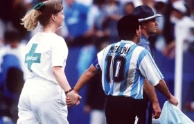 Diego Maradona sale de la mano con una voluntaria de la FIFA que lo conduce al examen antidoping. 