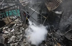 Un hombre usa un extintor en los escombros de una vivienda destruida por un ataque con carro bomba en el Cauca