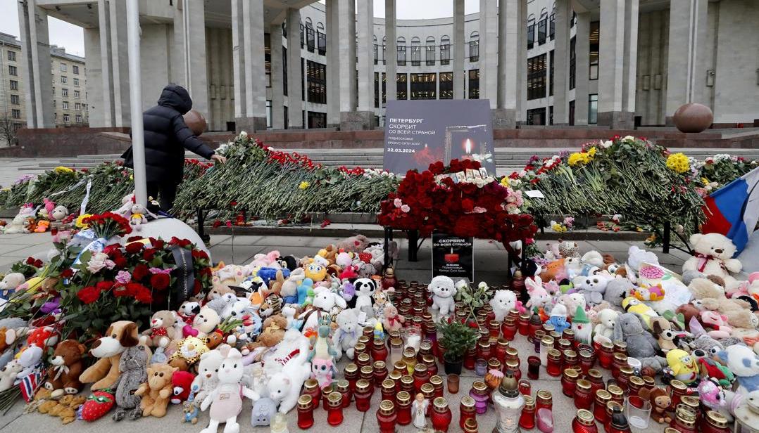 Una mujer deposita flores en un monumento improvisado frente a la Biblioteca Nacional Rusa.