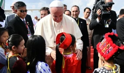 El papa Francisco saluda a un grupo de niños vestidos con trajes tradicionales a su llegada al aeropuerto internacional de Rangún, Birmania.