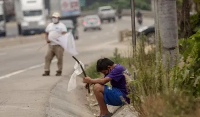 Un adolescente ondea una bandera blanca en una carretera pidiendo ayuda. 
