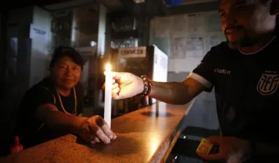 Ciudadanos ecuatorianos encienden una vela ante los apagones de los últimos días. 