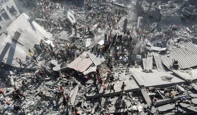 Palestinos buscan víctimas y supervivientes entre los escombros de un edificio residencial derribado.