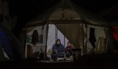 Una mujer palestina y su hijo que huyeron con su familia del norte de la Franja de Gaza se sientan dentro de su refugio en Deir al Balah, sur de la Franja de Gaza