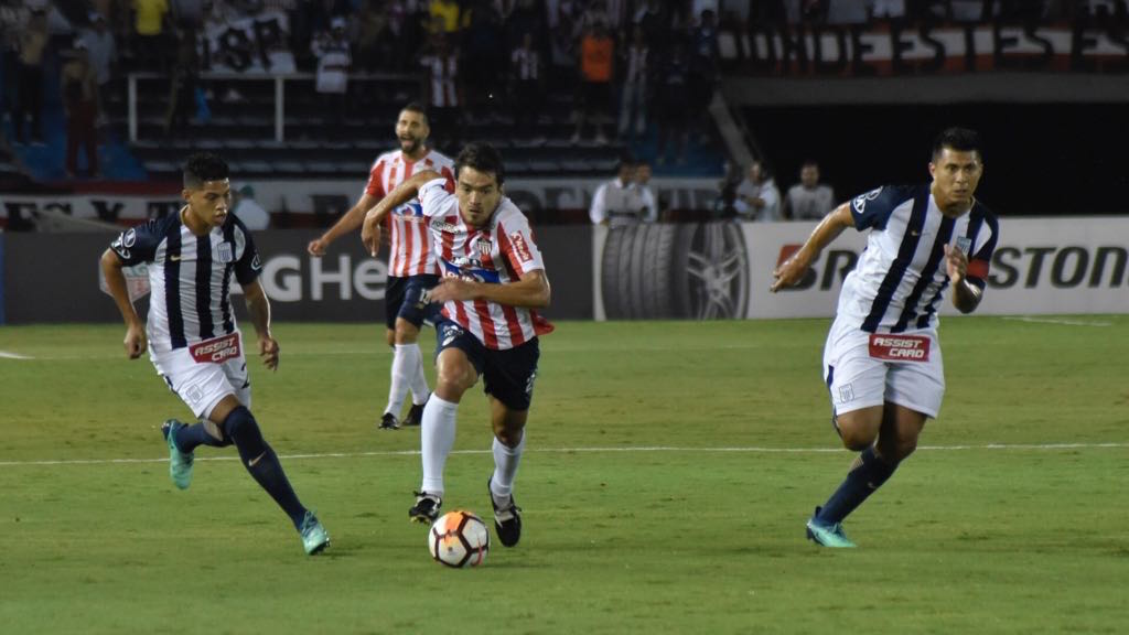 Sebastián Hernández atacando entre dos rivales.