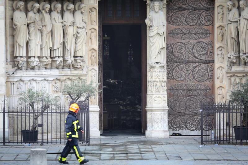 Un bombero observa los escombros apilados en el interior de la catedral de Notre Dame, mientras pasa por delante del edificio.