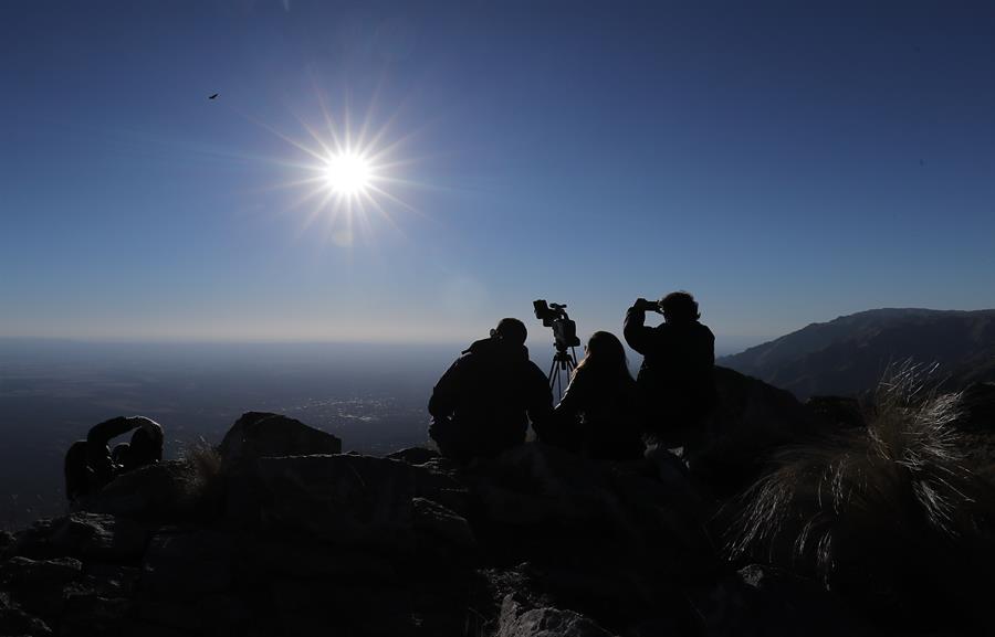 Espectadores al filo de la montaña, observan el sol durante el eclipse solar total, este martes en la ciudad de Merlo, San Luis (Argentina).