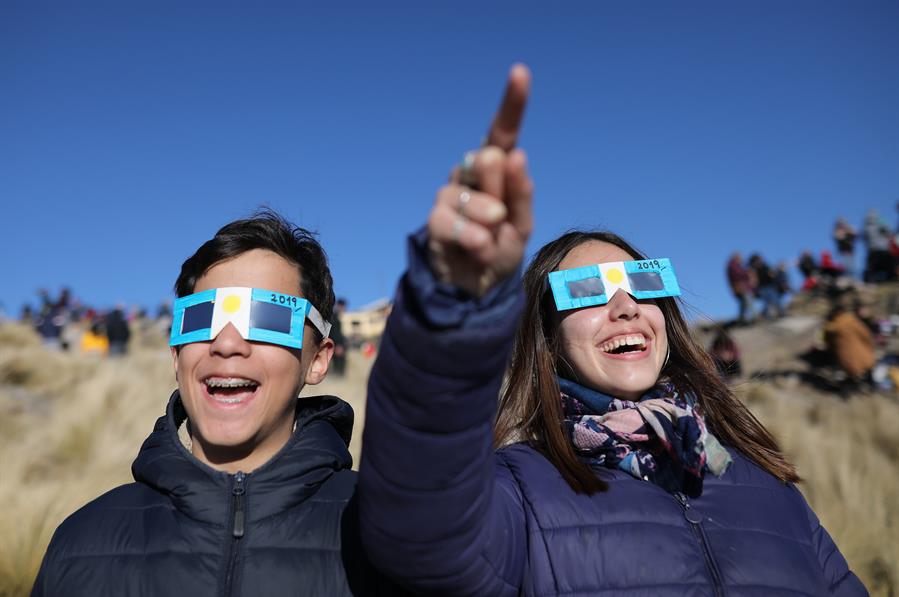 Dos niños con anteojos protectores miran el sol antes del Eclipse solar total este martes, en Merlo, San Luis (Argentina). 