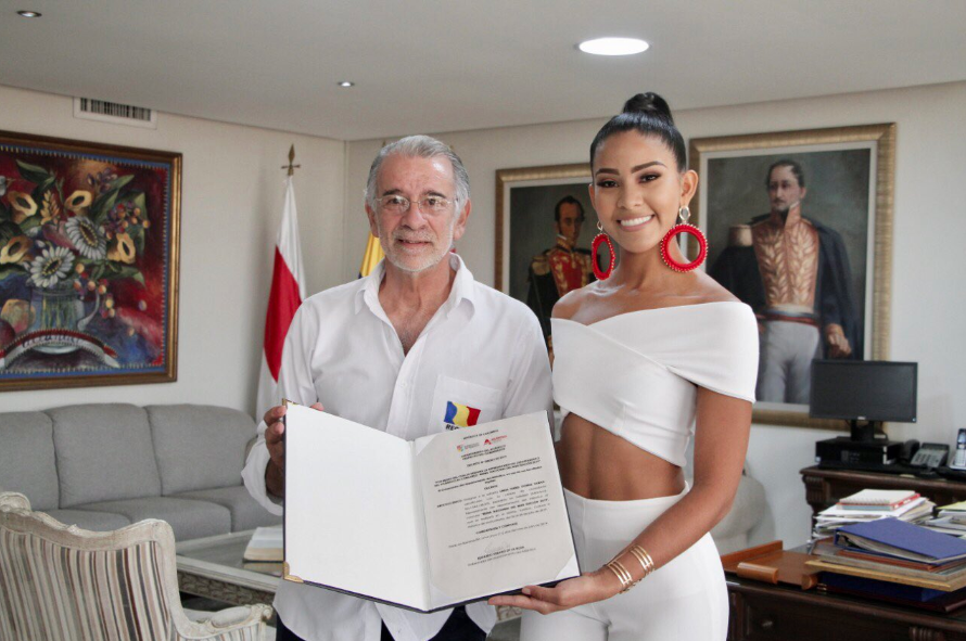 Linda Gómez recibiendo de las manos del Gobernador Eduardo Verano el decreto oficial.