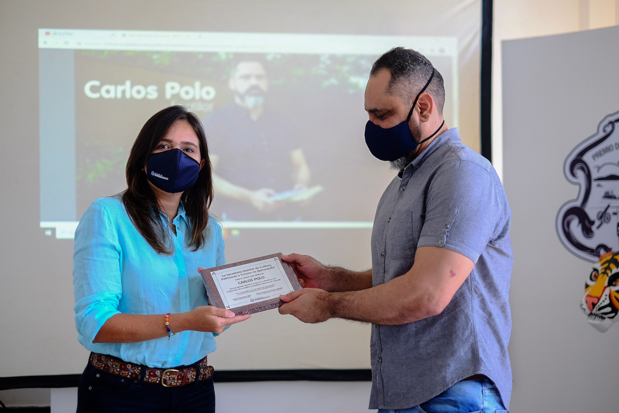El periodista y escritor Carlos Polo recibe el reconocimiento de la secretaria de Cultura, María Teresa Fernández.