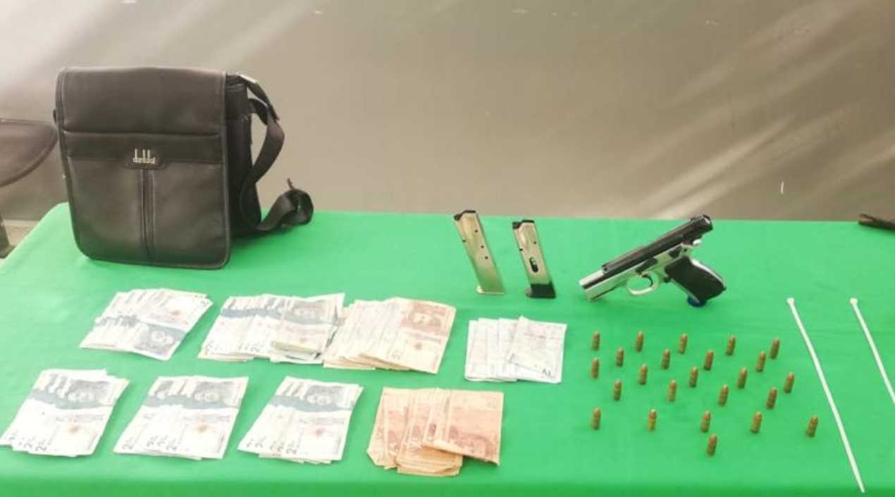 El dinero recuperado y el arma que le hallaron a los presuntos delincuentes. 