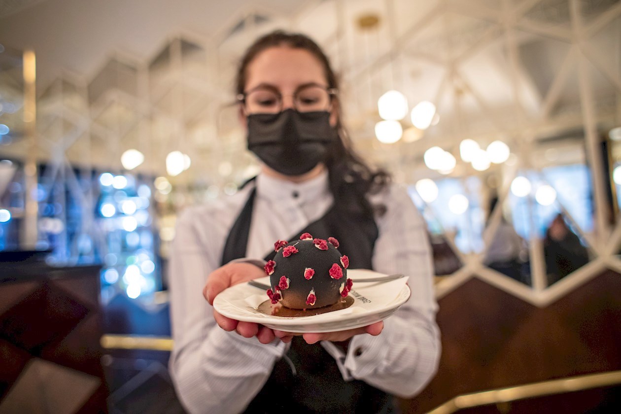 Una empleada del famoso café Cerna Madona en Praga ofrece uno de los postres con forma de coronavirus.